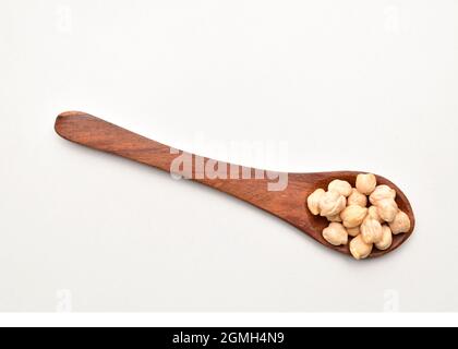 Pois chiches crus dans une cuillère en bois isolée sur fond blanc Banque D'Images