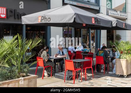 Les personnes assises à l'extérieur des tables et dînant en plein air dans un restaurant Pho, manger de la cuisine vietnamienne de rue, Royaume-Uni Banque D'Images