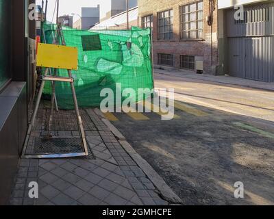 Panneau vierge devant une zone de travail d'entretien de rue clôturée sur une rue de ville Banque D'Images