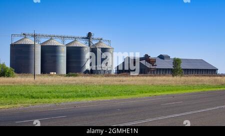 Quatre grands silos et stockage se trouvent à côté de la route et du chemin de fer près de Narrandera en Nouvelle-Galles du Sud Banque D'Images