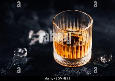 Chuchoter avec de la glace sur une table sombre contre le fond des bouteilles de bar Banque D'Images