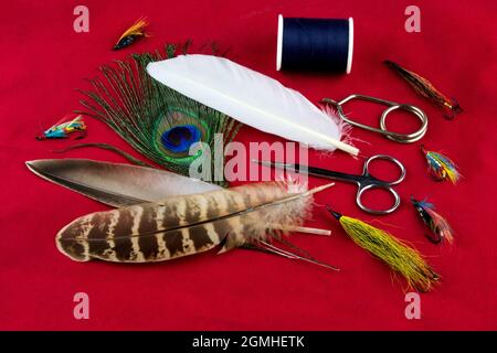 Mouche de pêche nouant des outils et des plumes sur un chiffon de table rouge marbré Banque D'Images