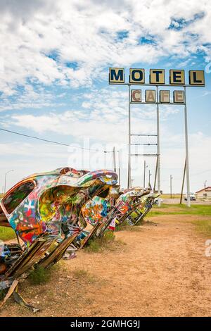 Des coléoptères Volkswagen peints à moitié enterrés à un angle au Slug Bug Ranch Amarillo Texas sur la route 66 avec l'ancien motel et le panneau de café Banque D'Images