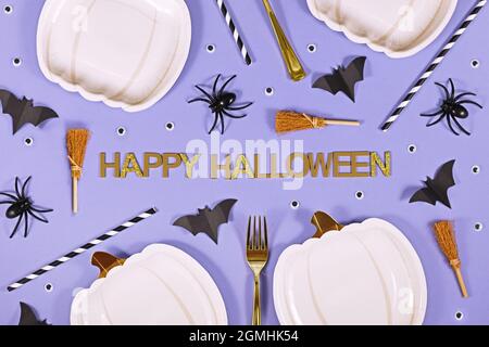 Halloween Party Flat lay avec texte « Happy Halloween », plaques en forme de citrouille, balais de sorcières, araignées et chauves-souris sur fond violet Banque D'Images