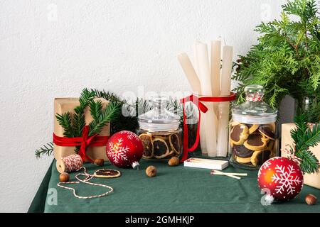 Table de Noël ou du nouvel an décorée de façon festive, branches de thuja et d'épinette, bougies et boules de Noël, biscuits aux pépites de chocolat dans un pot Banque D'Images