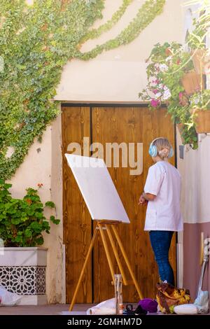 Artiste méconnaissable femme peint sur toile dans une allée à l'extérieur. Concept peinture à l'extérieur, artistes à l'extérieur Banque D'Images