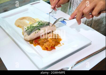 Filet de merlu sur une assiette blanche avec poivrons rouges et purée de pommes de terre Banque D'Images