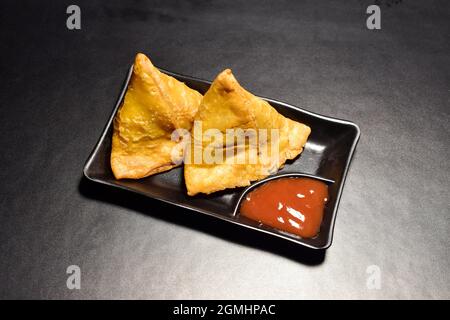 Samosa à la sauce dans l'assiette, célèbre en-cas asiatique farci samosa Banque D'Images