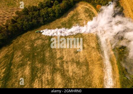 Vue aérienne d'un tracteur qui répand de la chaux sur les champs agricoles pour améliorer la qualité du sol après la récolte d'automne. L'utilisation de poudre de chaux pour neutraliser Banque D'Images