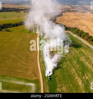 Vue aérienne d'un tracteur qui répand de la chaux sur les champs agricoles pour améliorer la qualité du sol après la récolte d'automne. L'utilisation de poudre de chaux pour neutraliser Banque D'Images