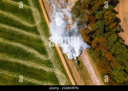 Vue aérienne d'un tracteur qui répand de la chaux sur les champs agricoles pour améliorer la qualité du sol après la récolte d'automne. L'utilisation de poudre de chaux pour neutraliser Banque D'Images