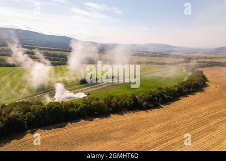 Vue aérienne d'un tracteur qui répand de la chaux sur les champs agricoles pour améliorer la qualité du sol après la récolte d'automne. L'utilisation de poudre de chaux pour neutraliser Banque D'Images