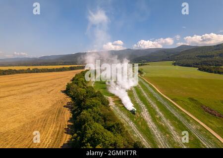 Vue aérienne d'un tracteur qui répand de la chaux sur les champs agricoles pour améliorer la qualité du sol après la récolte d'automne. L'utilisation de poudre de chaux pour neutraliser Banque D'Images