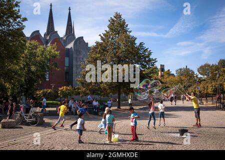 L'homme fait d'énormes bulles de savon dans le jardin du Rhin dans la vieille partie de la ville, le catéchrique, Cologne, Allemagne. Mann macht grosse Seifenblasen im Rhein Banque D'Images