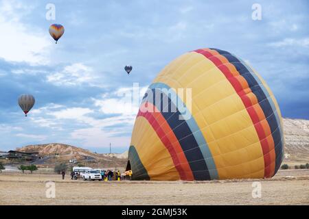 Touristes attendant l'équipage pour chauffer le ballon d'air à un point de lancement en Cappadoce, Turquie Banque D'Images