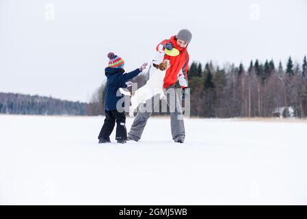 Concept de liaison familiale avec plus loin et fils jouant disque volant avec chien domestique Banque D'Images