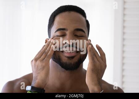 Beau homme africain toucher massages visage lisse peau parfaite Banque D'Images