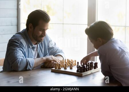 Petit garçon 8s avec père jouant aux échecs à la maison Banque D'Images