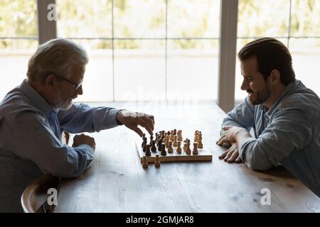 Vue latérale jeune homme avec un père mature jouant aux échecs ensemble Banque D'Images
