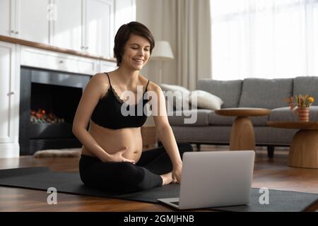 Femme enceinte regarder un cours de yoga pour les futures mamans sur ordinateur portable Banque D'Images