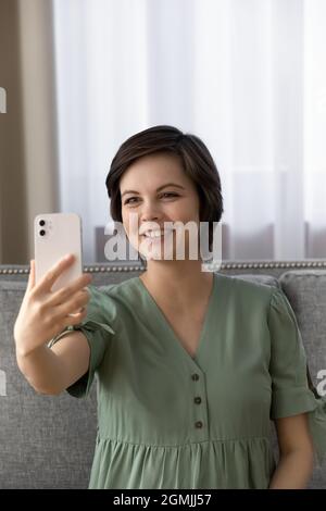 Belle femme s'attendant à un bébé assis sur un canapé prendre un joli selfie Banque D'Images