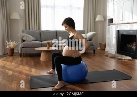 Joyeux future maman utiliser le tapis de yoga fitball pour faire des exercices Banque D'Images