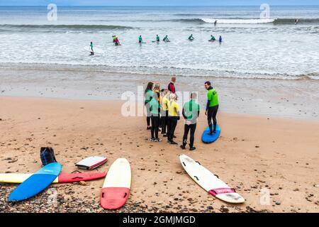 École de surf avec instructeur, élèves et planches de surf sur la plage à Saltburn by the Sea, Redcar et Cleveland District, North Yorkshire, Angleterre, Banque D'Images