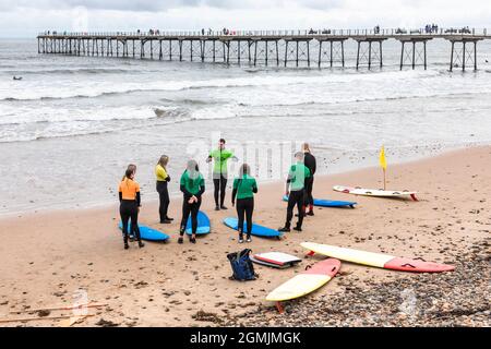 École de surf avec instructeur, élèves et planches de surf sur la plage à Saltburn by the Sea, Redcar et Cleveland District, North Yorkshire, Angleterre, Banque D'Images