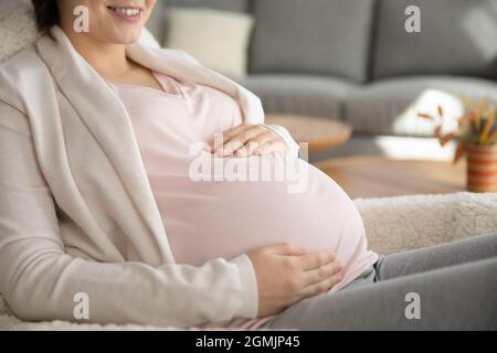 Jeune femme souriante future maman tenant les mains sur le ventre de la grossesse Banque D'Images