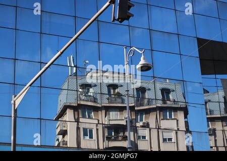 Bâtiment reflété dans un autre bâtiment avec des fenêtres en miroir, belle journée Banque D'Images