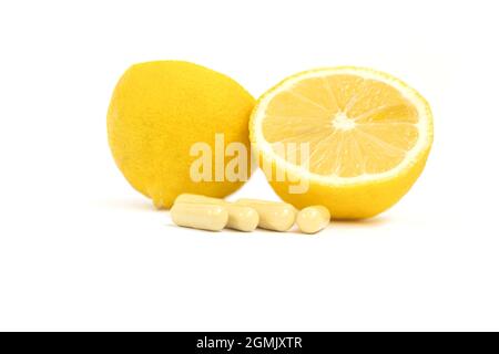Capsules de vitamines. Comprimés de vitamine C et citron jaune sur fond blanc. Banque D'Images