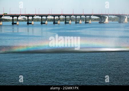 Arc-en-ciel sur les ruisseaux de la fontaine sur le fond du pont au-dessus de la rivière Dniepr. Les jets d'eau sont réfléchis comme un arc-en-ciel de Banque D'Images