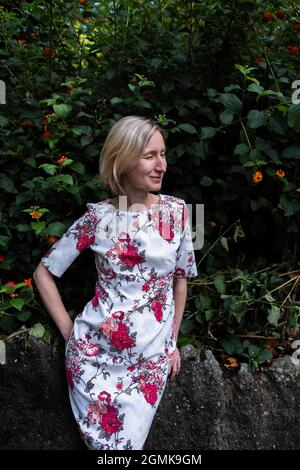 Une femme avec ses yeux fermés dans une robe brillante est debout dans le jardin. Banque D'Images