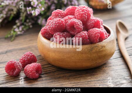 Bol en bois de framboises rouges fraîches sur une table de cuisine. Banque D'Images