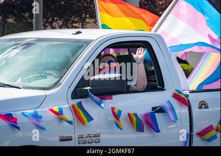 ROSEVILLE, CA, ÉTATS-UNIS - SEPT. 19, 2021: Atom Vaughn, un homme trans, fait des vagues dans la barbe arc-en-ciel pendant qu'il conduit son camion décoré avec un arc-en-ciel et un drapeau trans. Banque D'Images