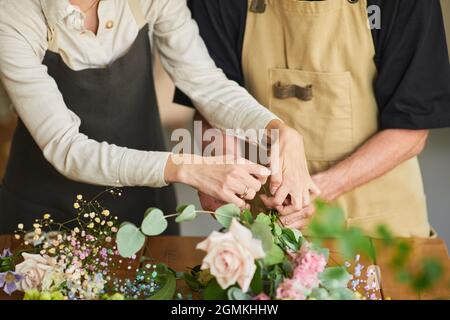 Gros plan de deux fleuristes en alignement de compositions florales dans un atelier confortable, espace de copie Banque D'Images