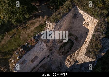Vue aérienne de la ruine médiévale du château gothique de Blatnica au sommet d'une colline au-dessus du village dans une forêt verdoyante avec des tours et des travaux de restauration en Slovaquie Banque D'Images