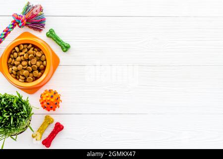 Sécher la nourriture pour chiens dans un bol avec des jouets et des friandises, vue du dessus Banque D'Images