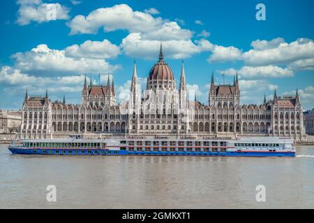 Vue d'été du Parlement hongrois construit dans le style néo-gothique le long du Danube avec une parfaite symétrie avec ciel bleu nuageux Banque D'Images