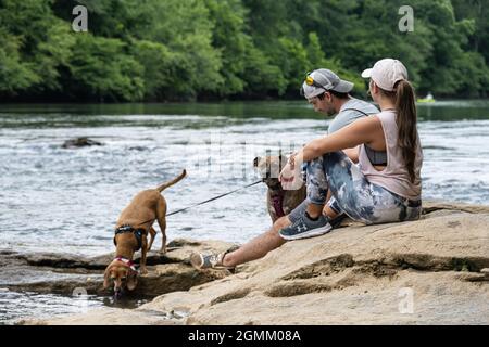 Couple avec des chiens se détendant le long de la côte rocheuse de la rivière Chattahoochee à Sandy Springs, juste au nord d'Atlanta, en Géorgie. (ÉTATS-UNIS) Banque D'Images