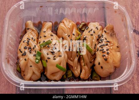 Boulettes chinoises cuites à la vapeur servies dans un récipient en plastique frais d'un service de livraison à domicile. Horizontal Banque D'Images