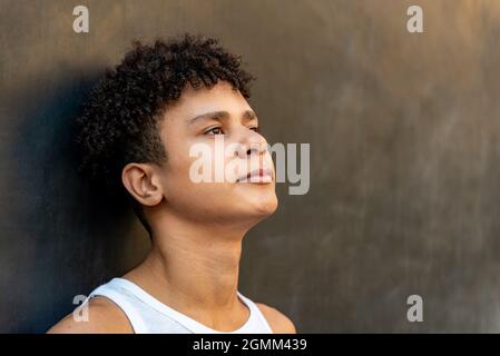 Afro latin homme adolescent contre un mur, regardant vers le haut. Banque D'Images