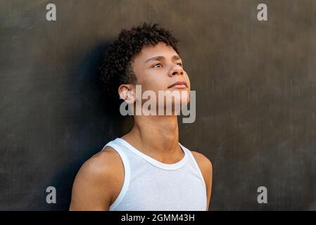 Afro latin homme adolescent contre un mur, regardant vers le haut. Banque D'Images