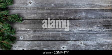 Bordure gauche de véritables branches de sapin sur fond rustique de planche en bois pour un joyeux Noël ou un joyeux concept de fête du nouvel an Banque D'Images