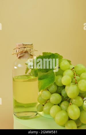 Huile de pépins de raisin.bouteille et bouquet de raisins verts sur podium . Huile de pépins de raisin biologique naturel organique. Banque D'Images