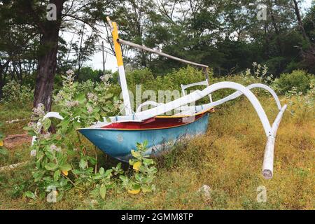 Vieux bateau en bois situé sur l'herbe dans l'île de Lombok, Indonésie. Banque D'Images