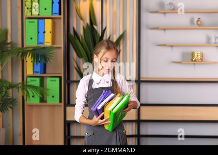 Portrait d'une fille dans un uniforme d'école avec un livre entre ses mains. L'enfant lit un manuel. Préparer une écolière pour une leçon ou un examen scolaire Banque D'Images