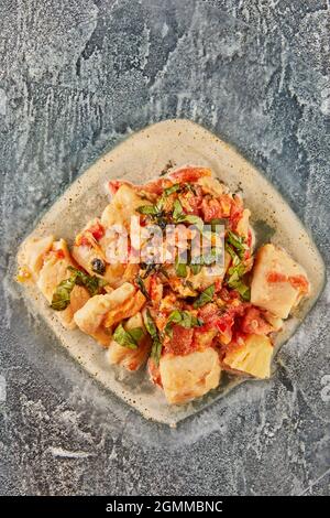 Poisson-basse avec tomates fenouil et basilic dans la sauce sur une assiette de verre. Pose à plat Banque D'Images