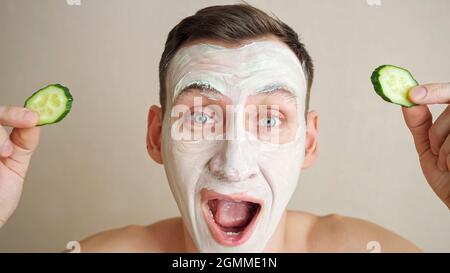 Un jeune homme avec un masque sur le visage joue avec des anneaux de concombre et fait des grimaces Banque D'Images