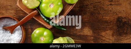 Tomatillos, tomates vertes, panorama avec un lieu pour le texte. Ingrédients de cuisine mexicaine sur fond de bois rustique sombre, photo de haut Banque D'Images